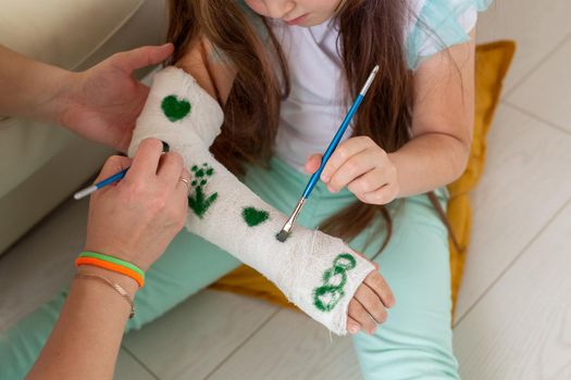 Mother and daughter drawing picture on bandage using paints. Play therapy concept
