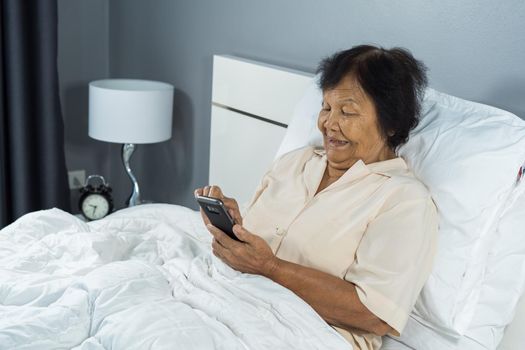 senior woman using mobile phone on a bed