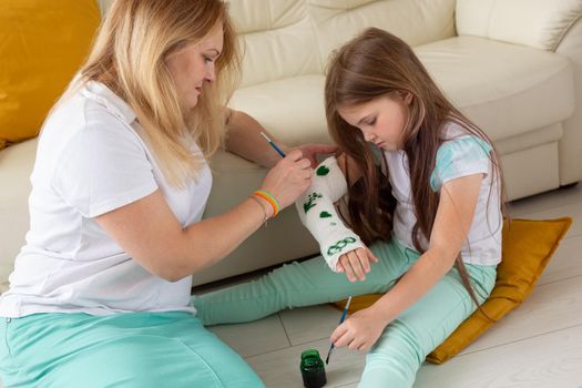 Mother and daughter drawing picture on bandage using paints. Play therapy concept