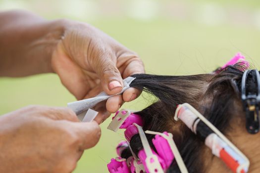 hand of a hairstylist doing a perm rolling the hair of senior woman