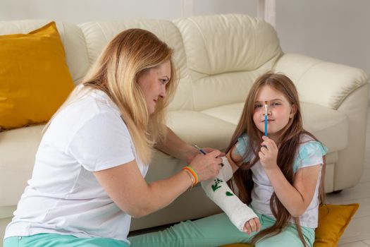 Mother and daughter drawing picture on bandage using paints. Play therapy concept