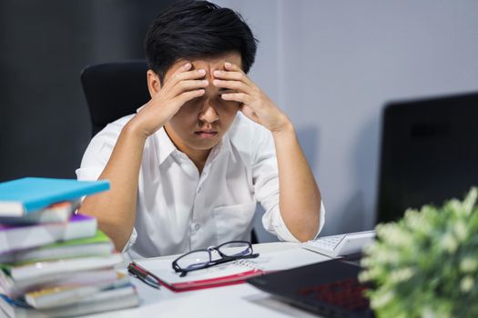 young stressed man studying with book and laptop