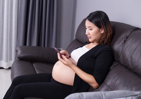 Portrait of pregnant woman using her mobile phone on sofa