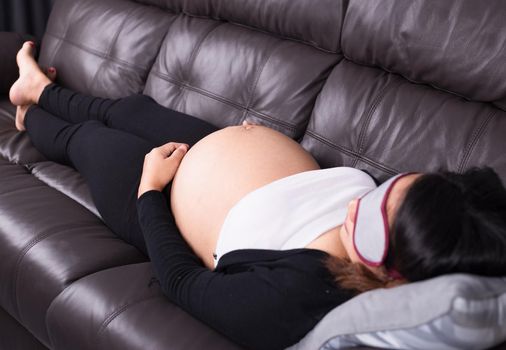 Pregnant woman sleeping on sofa in home