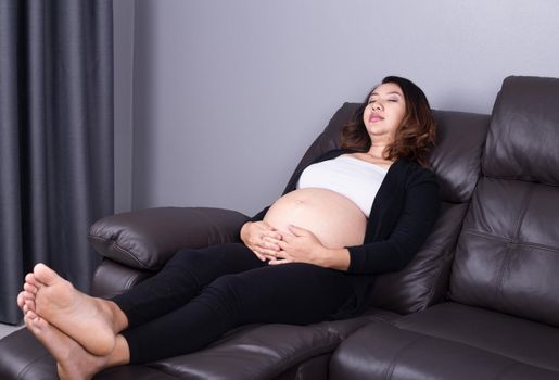 Pregnant woman sleeping on sofa in home