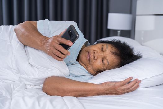 senior woman using mobile phone on a bed