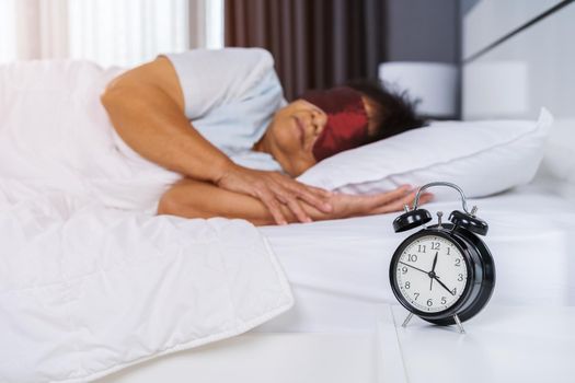 senior woman with eye mask sleeping on a bed