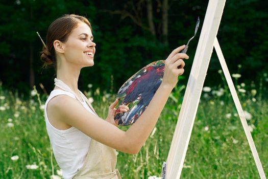 cheerful woman paints a picture palette nature landscape. High quality photo