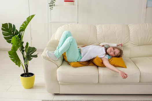 Child with a cast on a broken wrist or arm smiling and having fun on a couch. Positive attitude, recovery and kid.