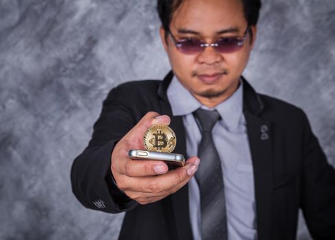 young business man with bitcoin and using mobile phone