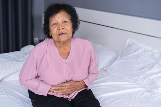 senior woman suffering from stomachache on bed at home