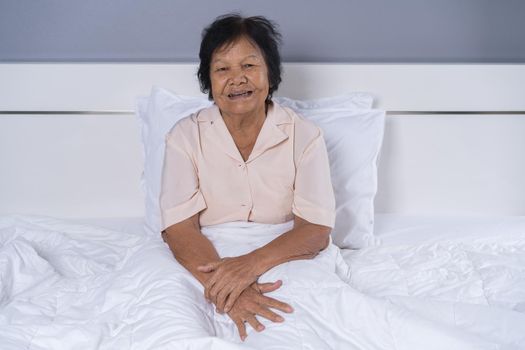 happy senior woman sitting on a bed