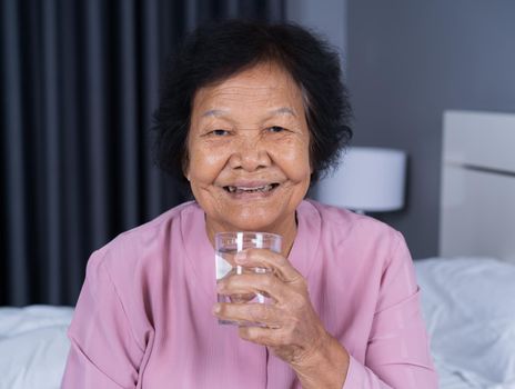 Senior woman drinking water in the bedroom