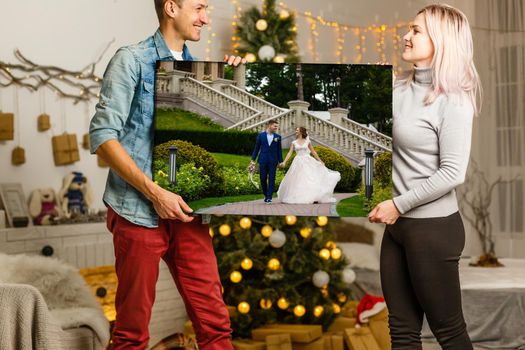 woman holding a photo canvas on the background of a Christmas interior.