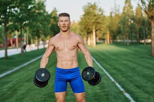 sporty man with pumped up body in park workout exercise. High quality photo