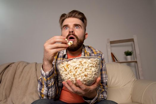 single man on the couch watching TV in a room