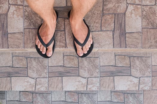 Men's legs in black flip flops go down and walk down the stairs. Walking style.