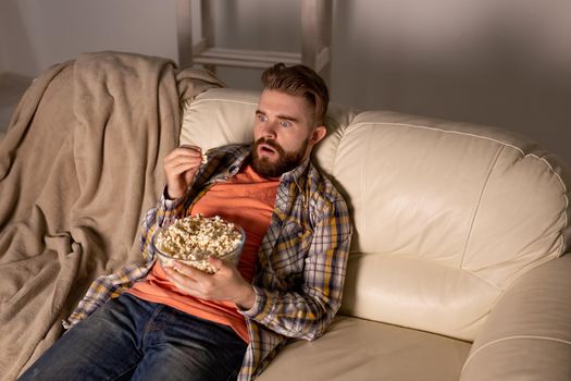 single man on the couch watching TV in a room