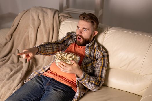 single man on the couch watching TV in a room
