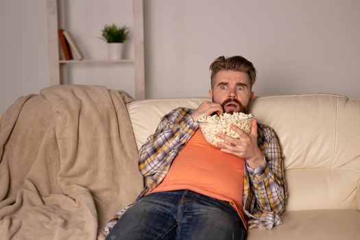 single man on the couch watching TV in a room