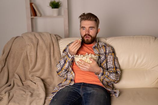 single man on the couch watching TV in a room