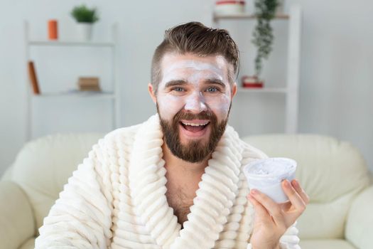 Bearded guy applying anti-wrinkle cream on his face. Skin care and spa for man concept