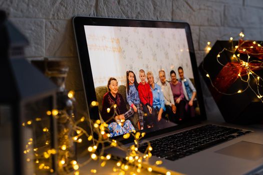 Happy parents hugging cute small kid daughter holding present giving Christmas gift to web camera during virtual family social meeting on video conference call party at home, laptop webcam view