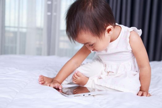 baby are looking to play and read tablet computer on bed at home