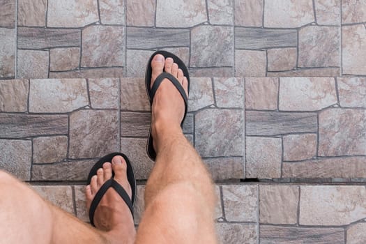 Men's legs in black flip flops go down and walk down the stairs. Walking style.