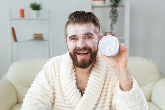 Closeup of handsome young man applying facial cream in front of mirror