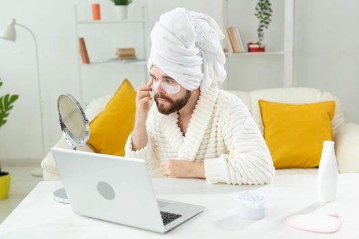 Bearded man applying eye patches on his face. Wrinkles and face home care for men