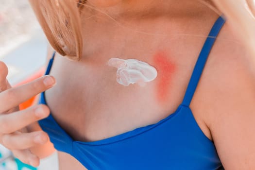 The hands of a young girl, in a blue swimsuit and shorts are going to smear on themselves a cream for sunbathing and protection from the sun against the background of the beach.