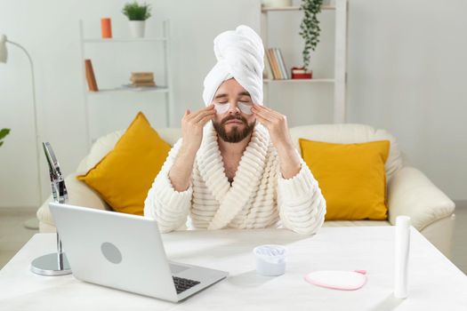 Bearded man applying eye patches on his face. Wrinkles and face home care for men