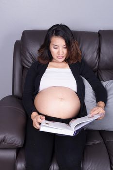 pregnant woman lying on sofa and reading a book