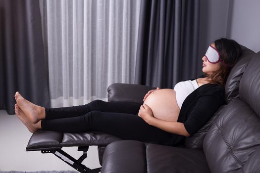 Pregnant woman sleeping on sofa in home