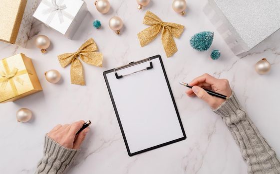 New Year Resolution and Motivation Concept. top view hands writing new year goals, resolution or shopping list on a blank paper. Mock up design