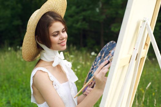 Woman in white dress outdoors artist drawing easel. High quality photo