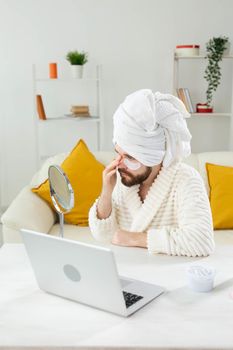 Bearded man applying eye patches on his face. Wrinkles and face home care for men