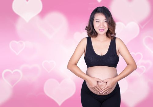 Pregnant Woman holding her hands in a heart shape on her belly on heart background