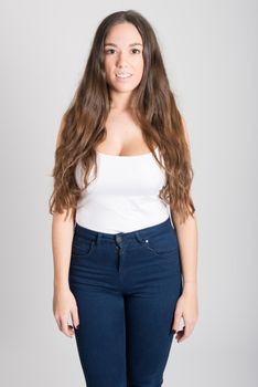 Portrait of young woman with long hair wearing white t-shirt and blue jeans on white background