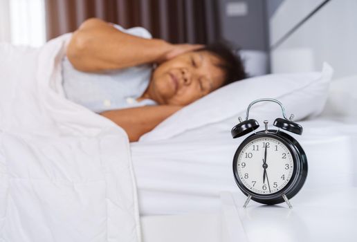 alarm clock wake up in the morning and senior woman close her ears 
