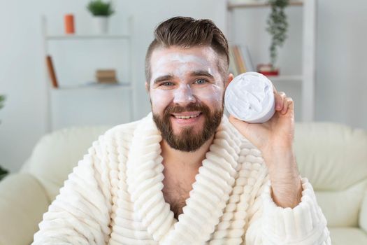 Bearded guy applying anti-wrinkle cream on his face. Skin care and spa for man concept