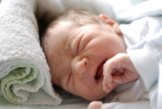 Newborn baby girl in hostpital bed craying. Caucasian female.