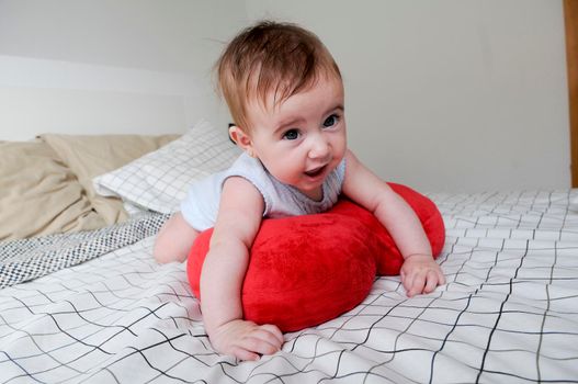 Happy baby girl, five months old, on the bed