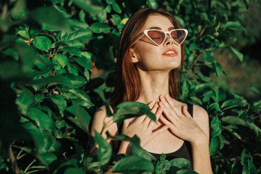 smiling woman wearing sunglasses green leaves nature fashion. High quality photo