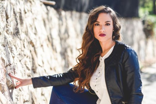 Portrait of woman with long hair wearing leather jacket in urban background