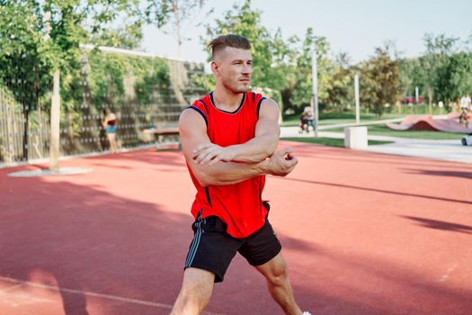 sports man in a red t-shirt on the sports ground doing exercises. High quality photo