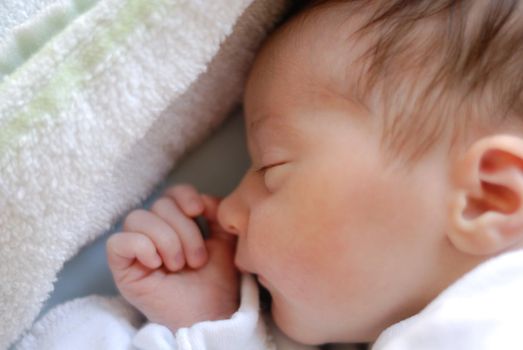 Newborn baby girl in hostpital bed sleeping. Caucasian female with adorable hand near her face.