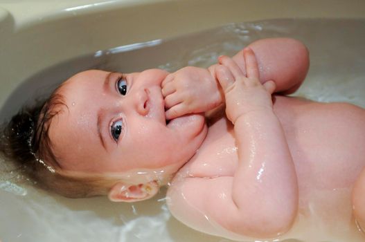 Baby girl four months old having her bath and crying