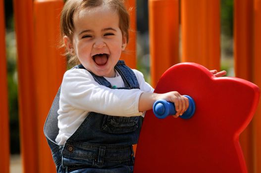 Happy little girl playing in a urban playground.